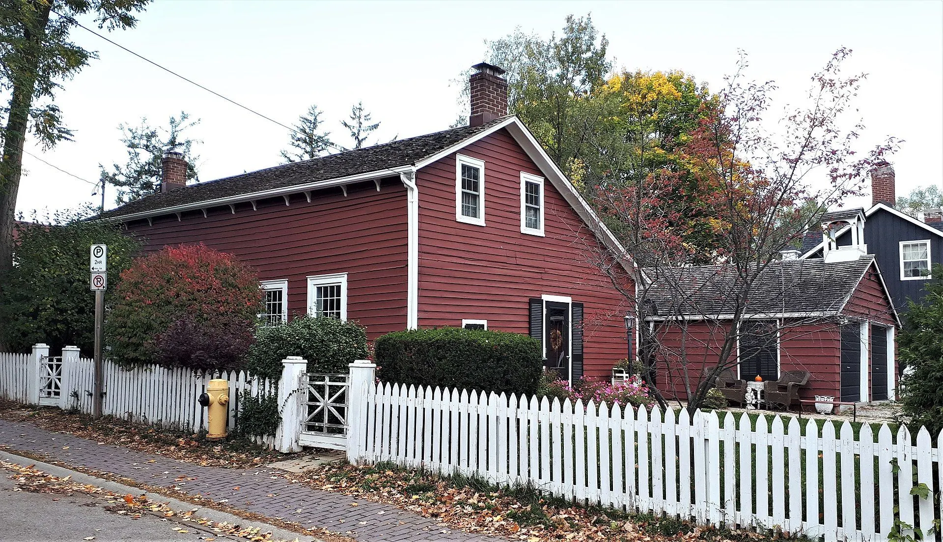 The red board-and-batten William Lane Cooper House behind a white picket fence in old Thornhill